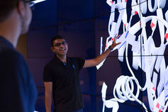 Informatics, Computing, and Engineering student stands in front of an IQ wall.